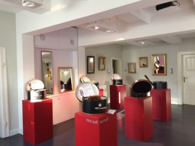 Im Foyer des Seesener Museums stehen roten Podeste mit offenen Hutschachteln, in den Hüten zum Aufprobieren einladen. An der Wand ringsum hängen Spiegel.