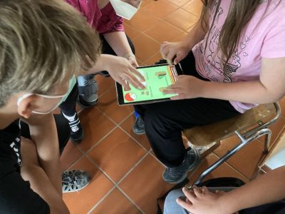 Vier Jugendliche spielen auf einem iPad das Spiel "KERAMIK-UM – Das Spiel".